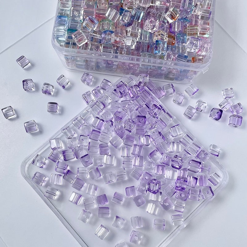 Purple rectangular faceted glass beads scattered on white, storage container