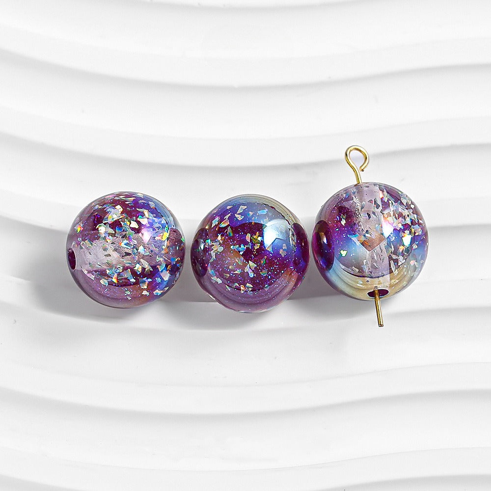 Three purple glitter resin beads on white; right bead has gold loop and pin