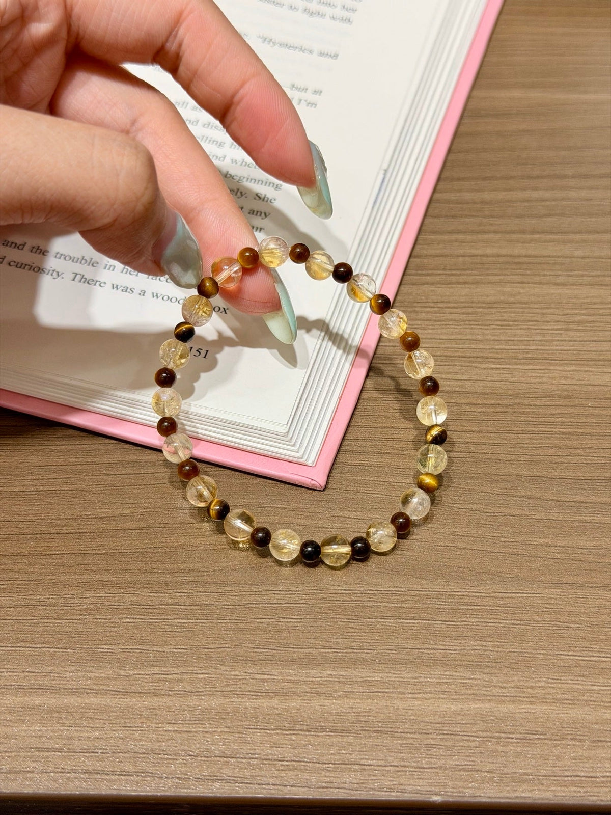 Beaded bracelet with yellow, dark brown, and black beads held by a hand