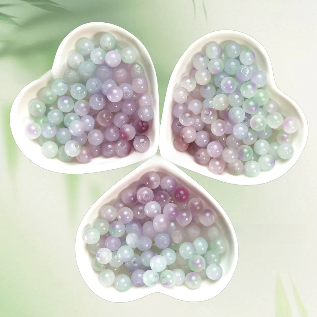 Three heart-shaped bowls of iridescent pastel lavender, mint, and purple beads