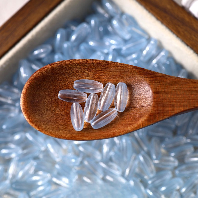 Clear transparent 4x9mm glazed glass long rice beads in a wooden spoon