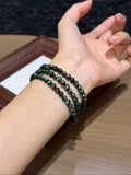 Verdant Dragon triple-wrap bracelet worn on the wrist — deep green seraphinite beads