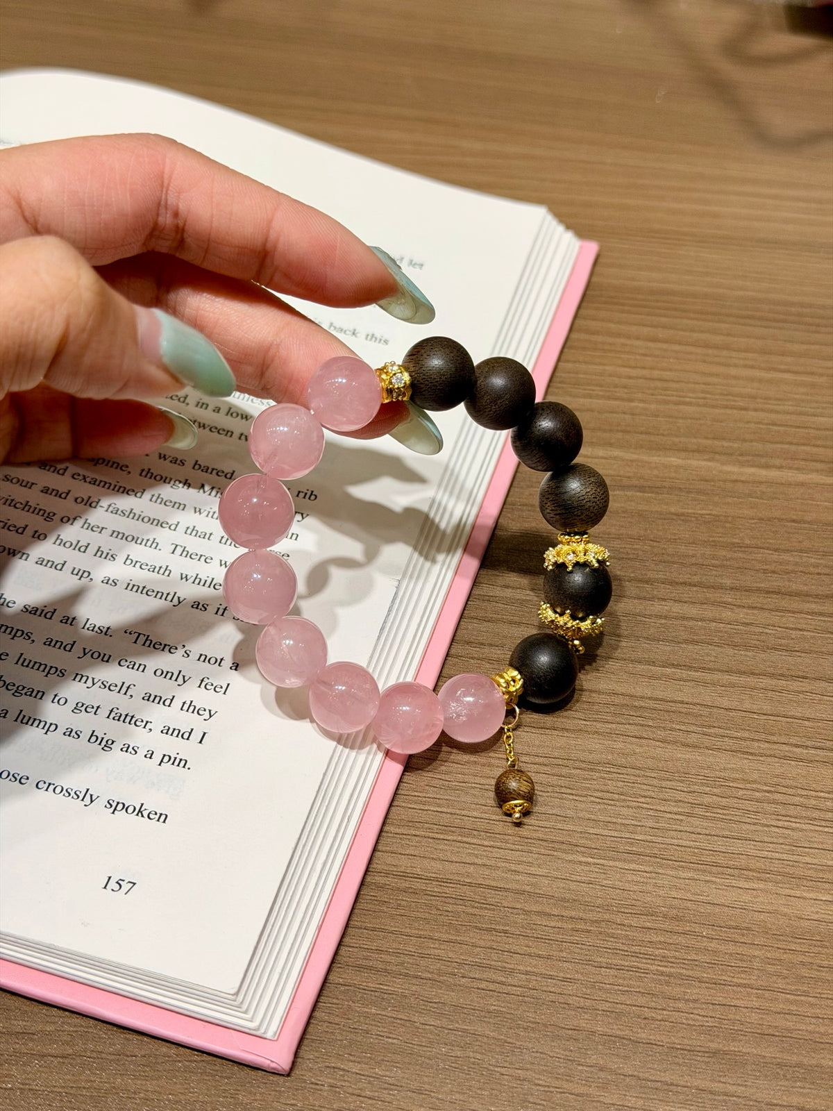 Pink quartz and sandalwood bead bracelet with gold accents worn on wrist