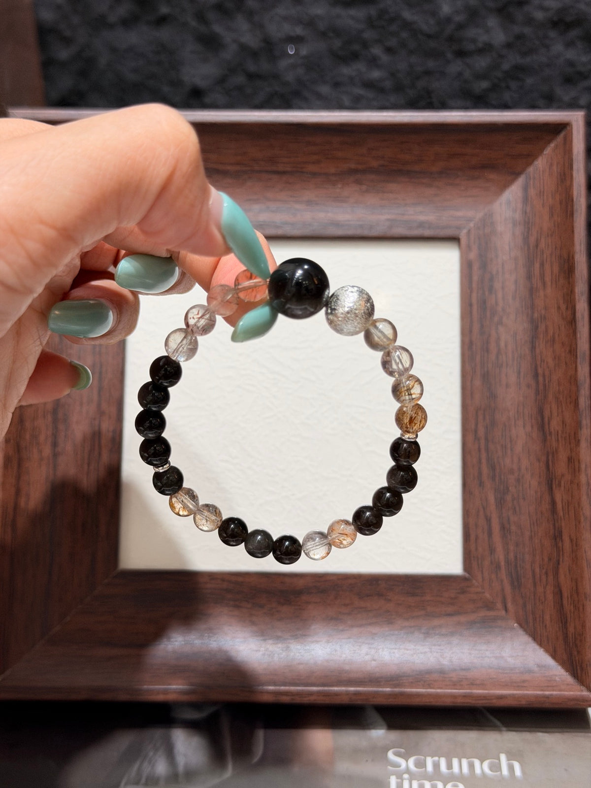 Hand holding black gold super seven and silver obsidian bracelet