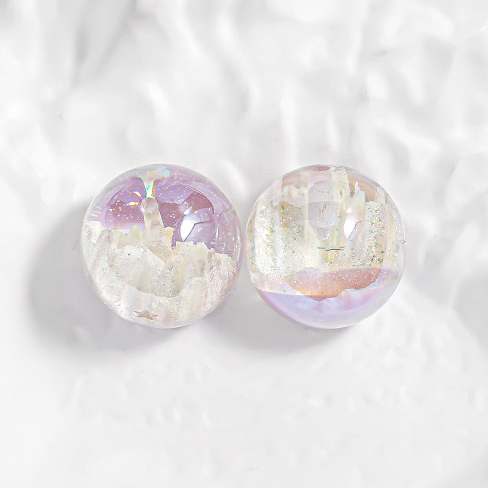 Two clear round resin cabochons with white crystal formations and pastel purple, pink, and gold glitter on white surface.