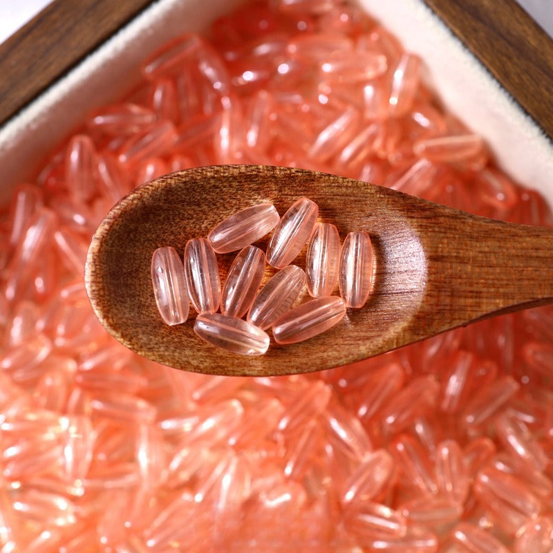 Pink translucent 4x9mm glazed glass long rice beads in a wooden spoon