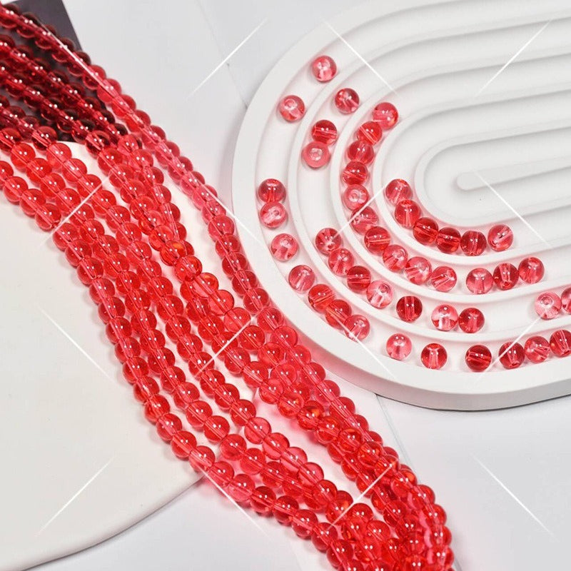 Red translucent round glass beads in strands on white, spiral bead holder