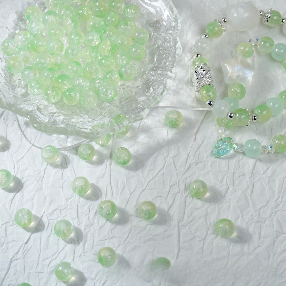 Light green glass bead bracelet beside a bowl of loose green beads