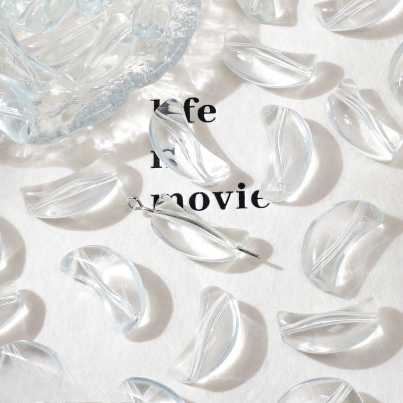 Clear crescent glass beads on white with 'life movie' text and a glass dish