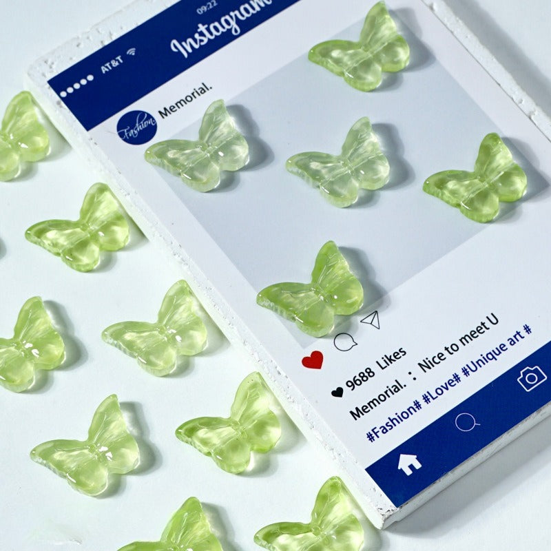 Clear butterfly-shaped glass beads on a white surface next to an Instagram post card