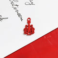 Small red decorative tree-shaped charm with ornate scroll design and loop