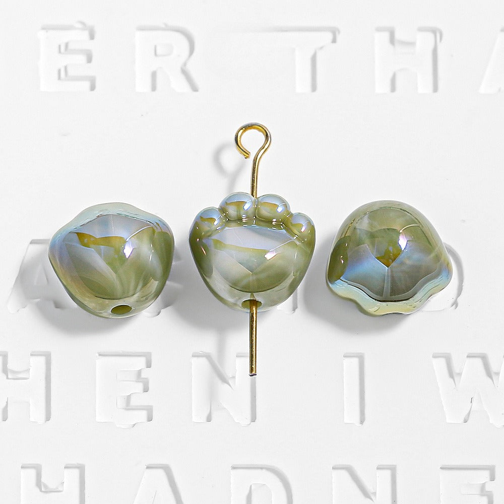 Three iridescent glass beads in pale sage green and gold on a white background.