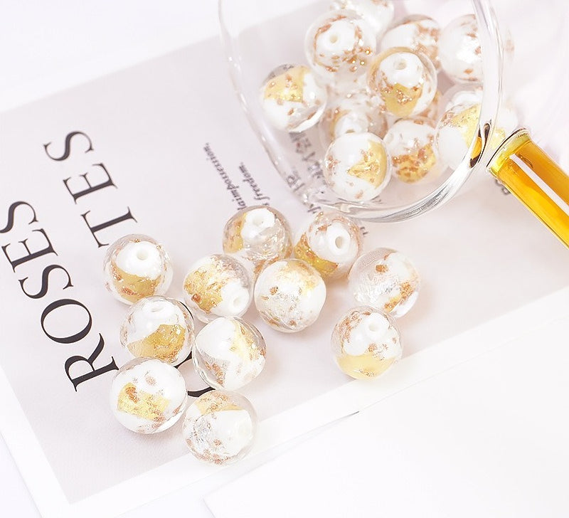 White and gold-flower glass beads spilling from a glass bowl onto a printed card