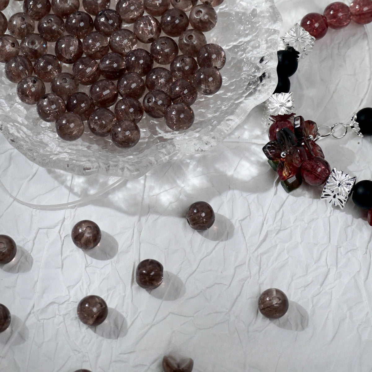 Brown translucent glass beads in a bowl beside a red and black beaded bracelet