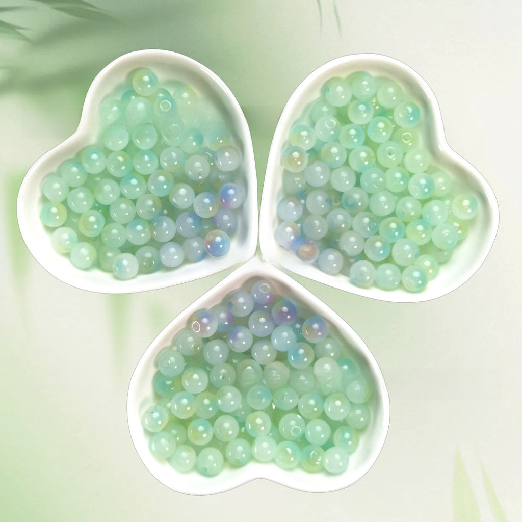 Three heart-shaped bowls of iridescent pale mint green and aqua beads