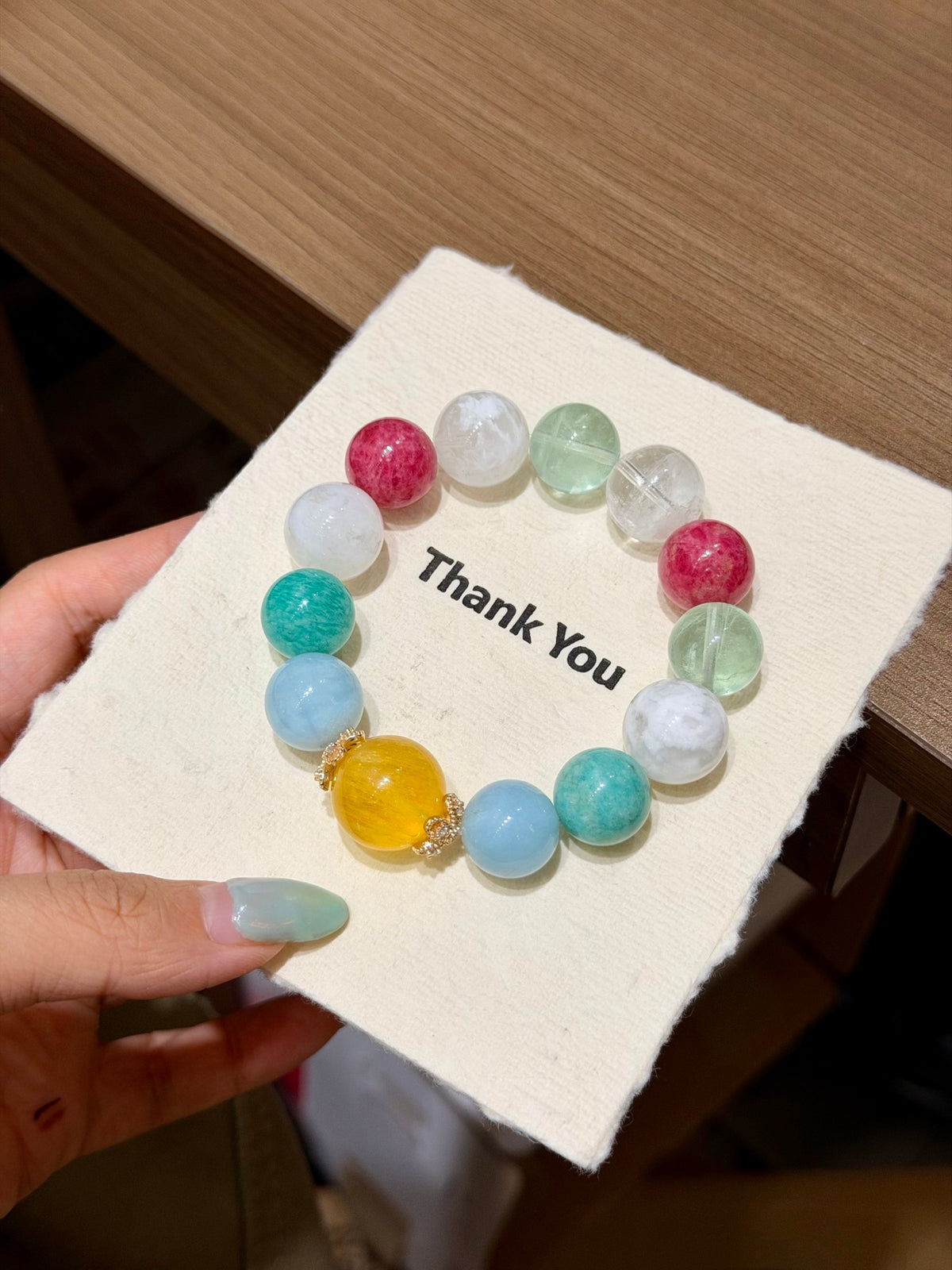 Woven Sea Reverie bracelet arranged in a circle on a thank-you card, showing the full bead layout