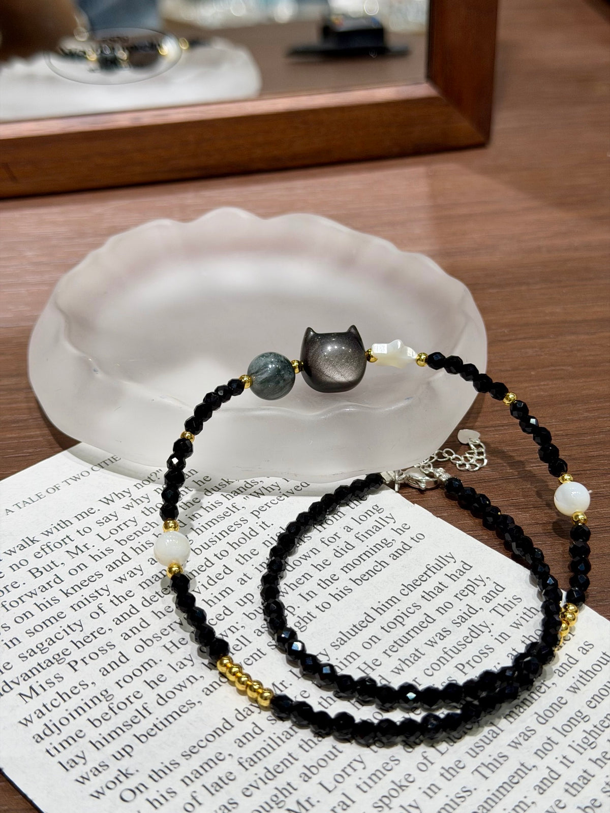 Midnight cat necklace with cat's eye shell beads on shell dish