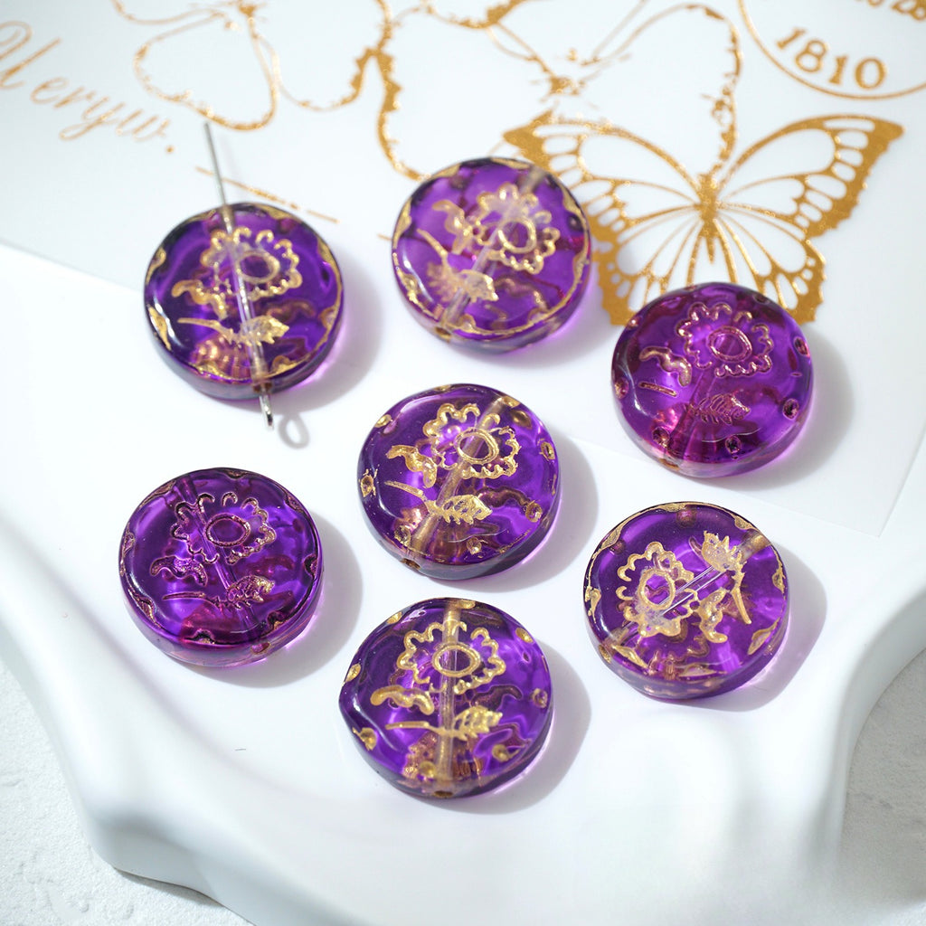 Seven grape purple 18mm gold-painted Czech-style glass sunflower beads on a white decorative surface