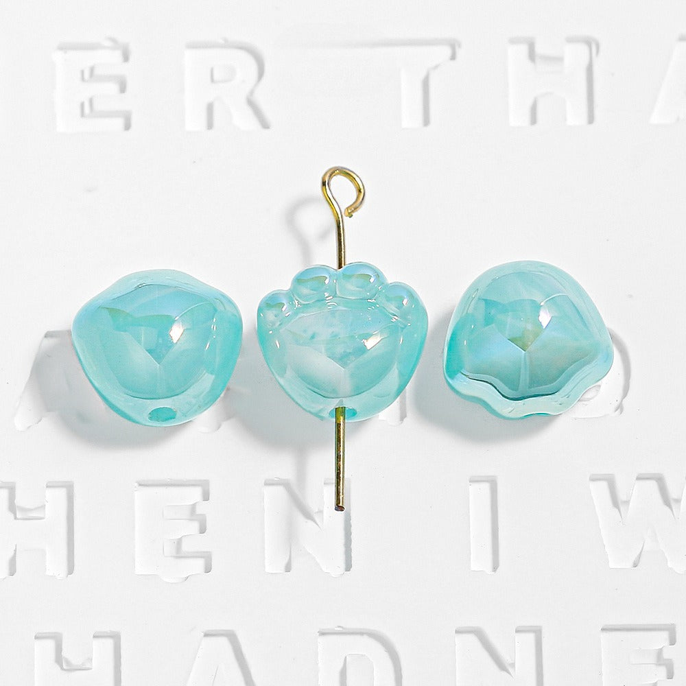 Three teal translucent paw-shaped beads, one on a gold eye pin
