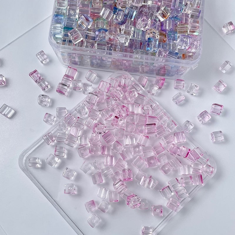 Clear rectangular glass beads with pink iridescent reflections on white