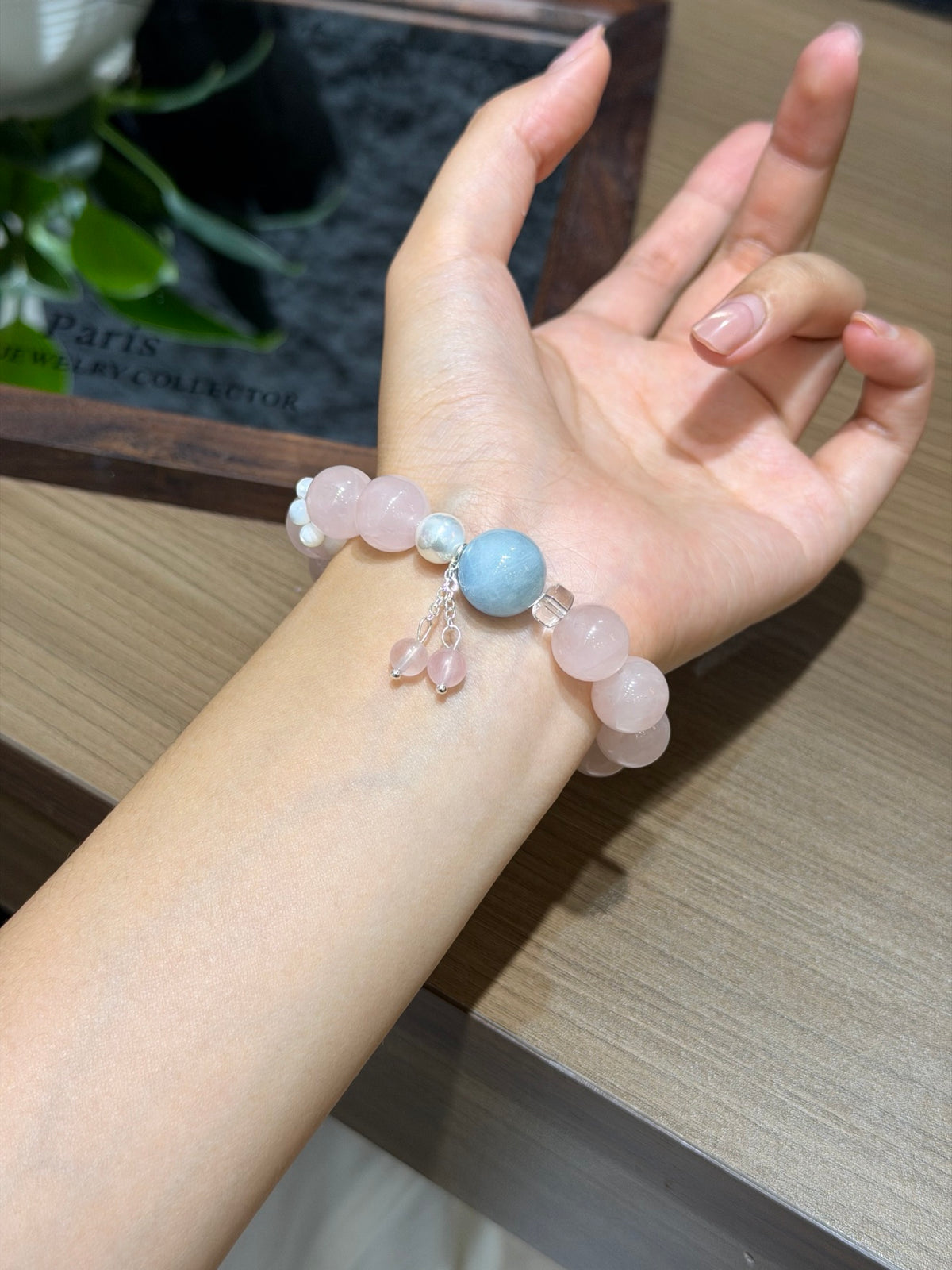 Close-up of peach mist bracelet with aquamarine and pink quartz tassel on wrist