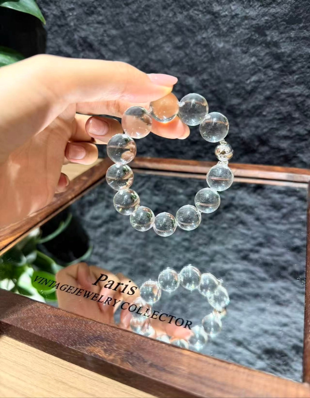 Hand holding the Crystal Bubble Reverie bracelet over a mirror, showing the AA-grade white quartz beads