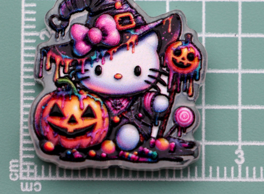 Hello Kitty candy witch acrylic charm with pink bows, jack-o'-lanterns, dripping paint on green cutting mat