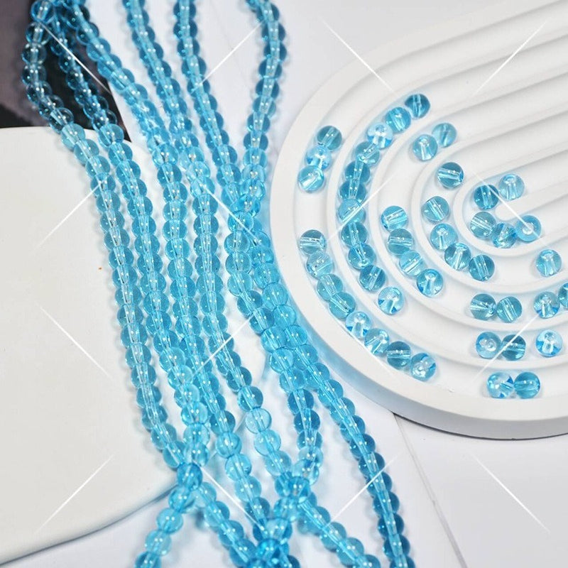 Light blue faceted glass beads on white, some draped in strands
