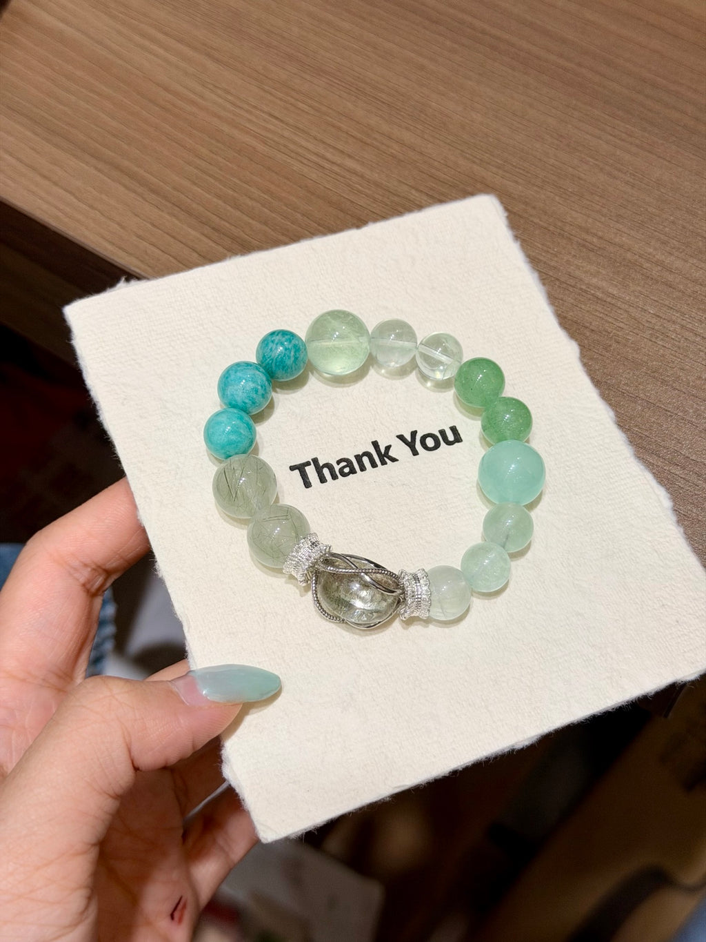 Forest mist green fluorite bracelet with cage charm worn on wrist