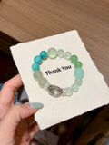 Forest mist green fluorite bracelet with cage charm worn on wrist