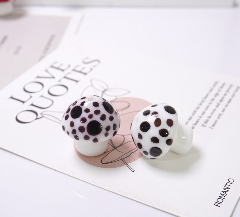 Pair of white glass mushroom beads with black polka dots on a LOVE QUOTES card