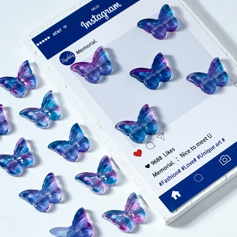 Iridescent blue, purple, and pink butterfly-shaped glass beads on a white surface