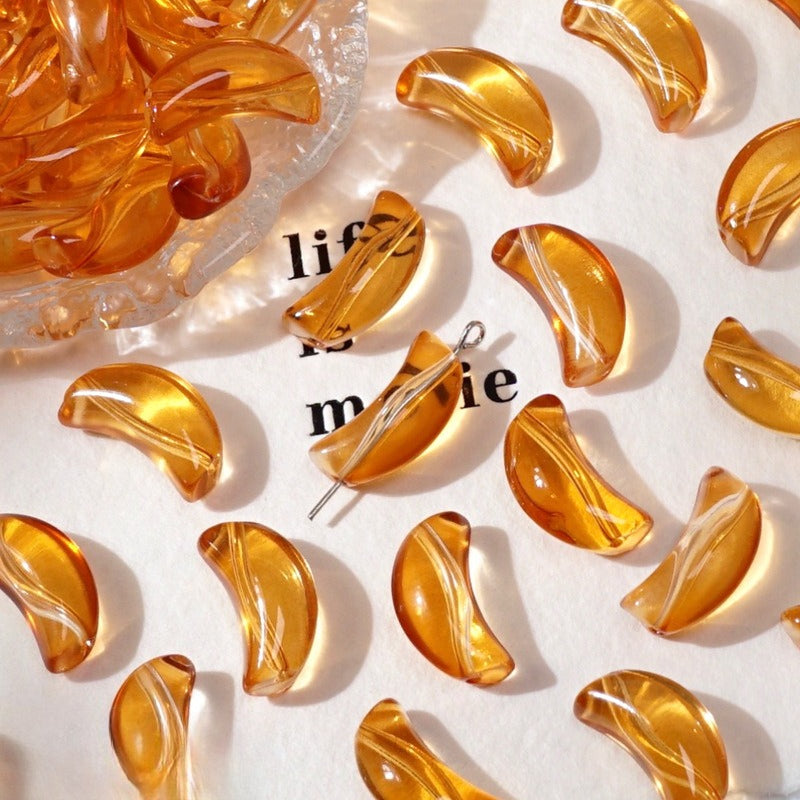 Amber-orange translucent crescent glass beads on white with a clear dish and text