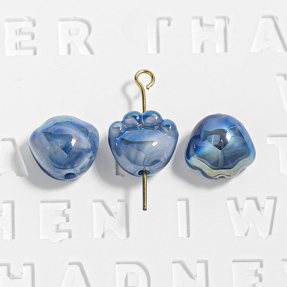 Three blue marbled paw-shaped beads, one on a gold eye pin