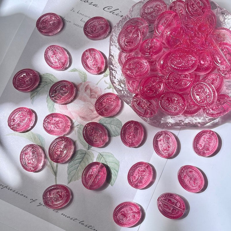 Pink translucent engraved glass rose beads beside a glass dish on floral paper