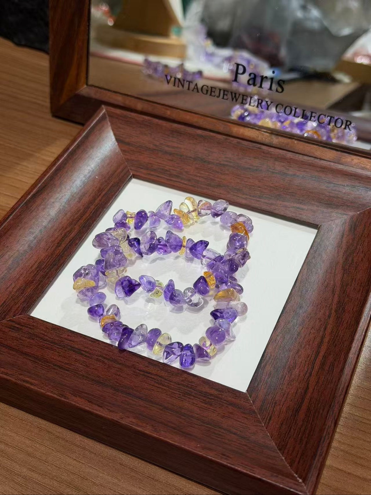 Ametrine chip bracelets coiled in a square wooden display tray on a table