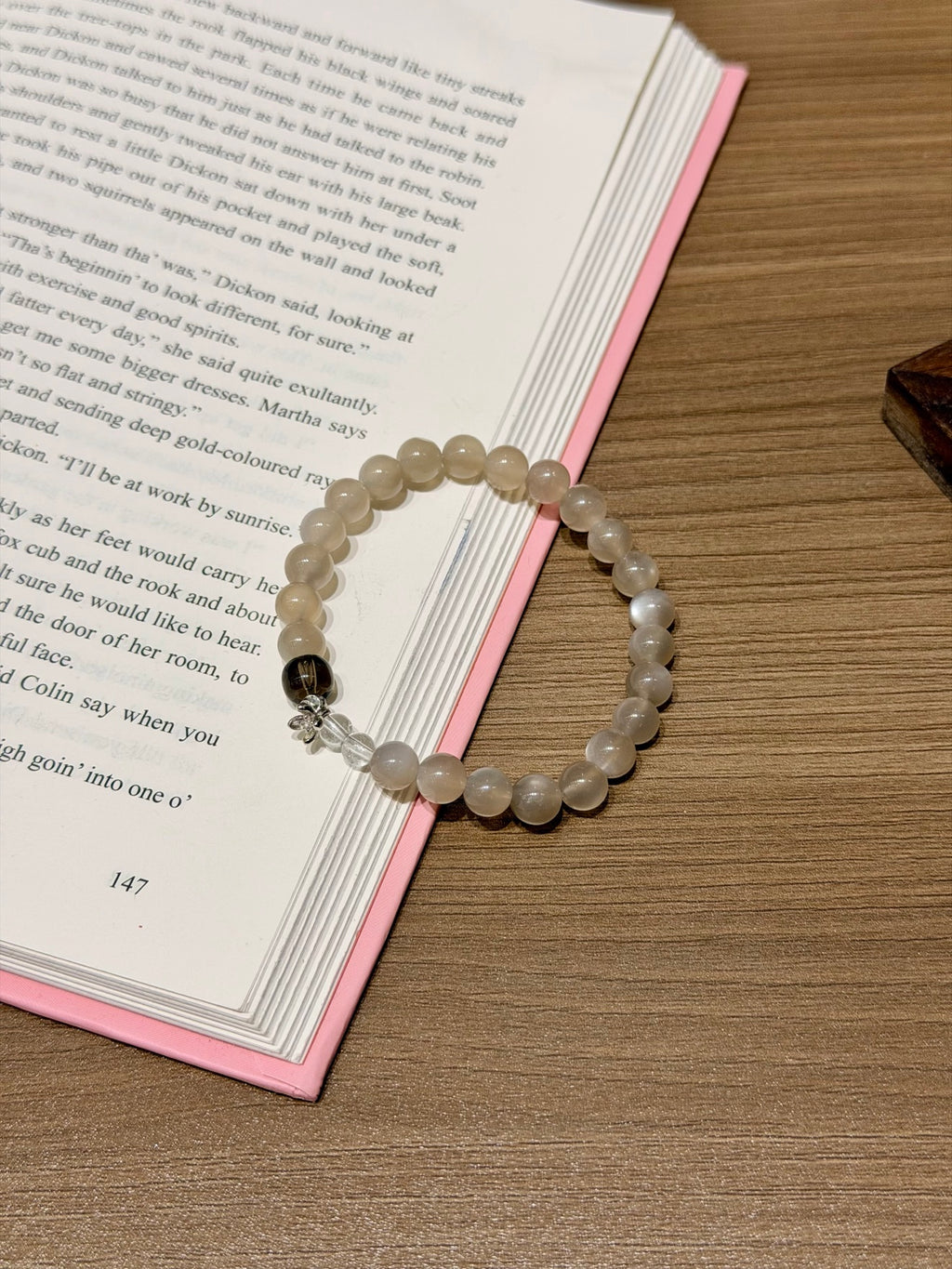 Milk tea moonstone beaded bracelet with smoky quartz accent on open book