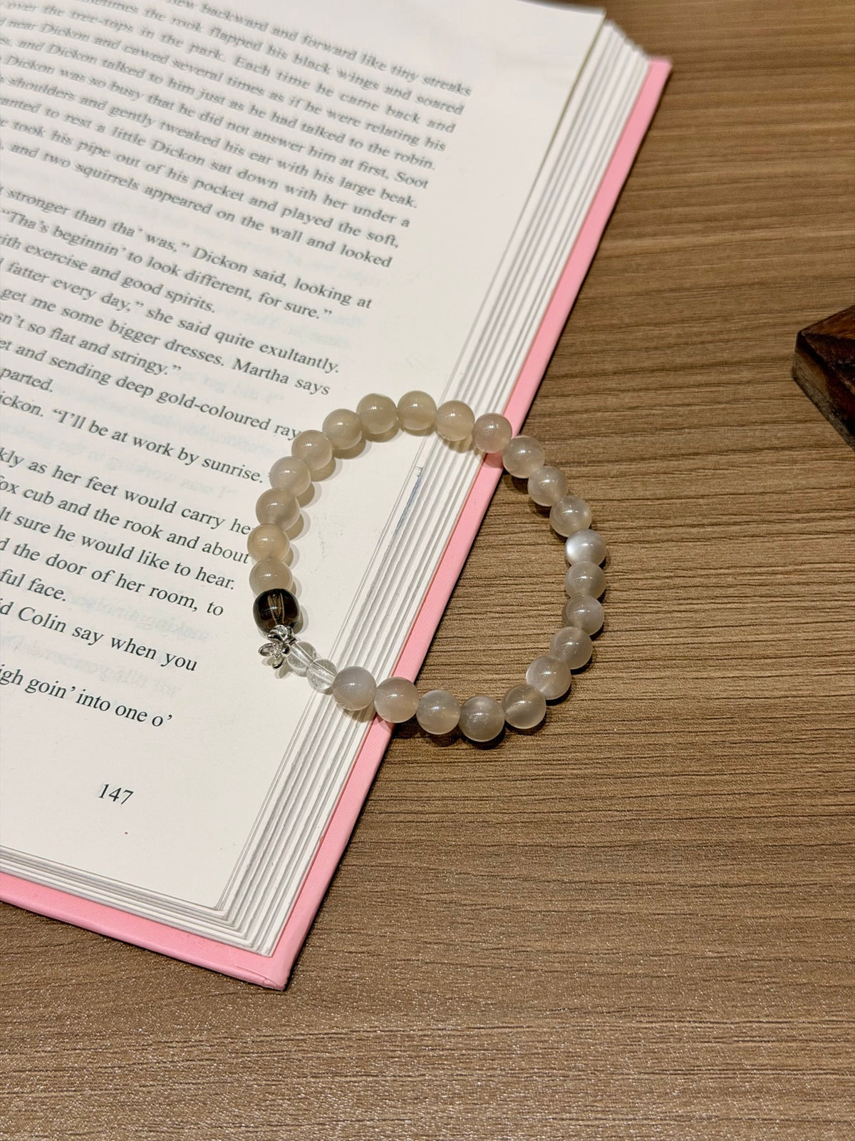 Milk tea moonstone beaded bracelet with smoky quartz accent on open book