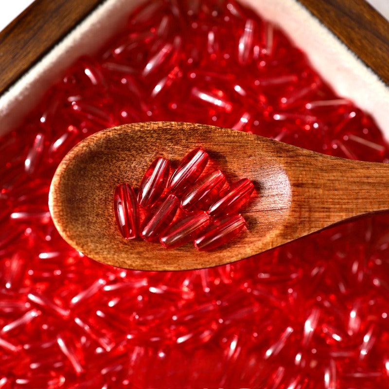 Red glazed glass long rice beads in a wooden spoon