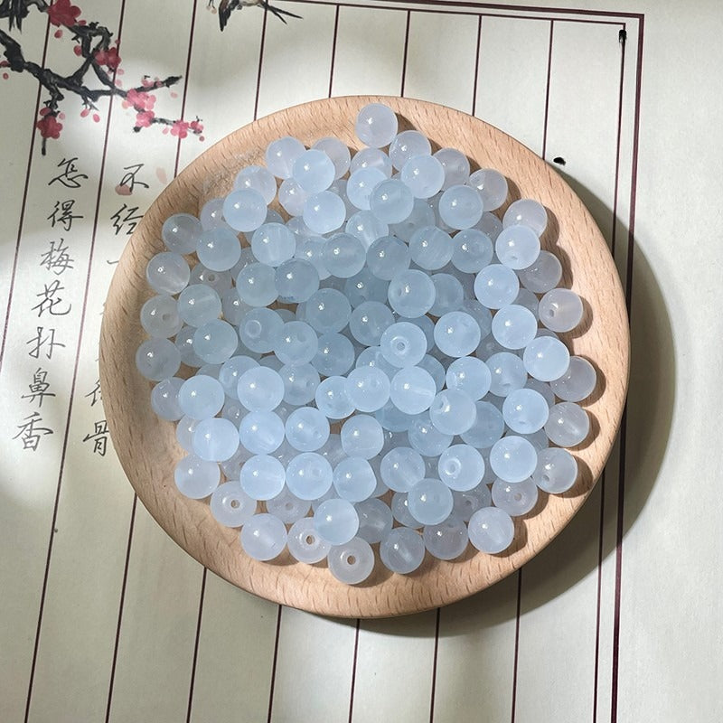 Translucent pale blue round beads on a wooden plate with calligraphy background