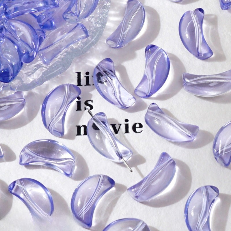 Purple translucent crescent glass beads on white with 'life is movie' text and a dish