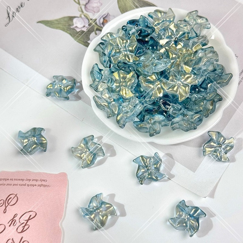 Ink blue 20mm carved glass windmill beads with gold powder in a white bowl, with loose beads scattered on white