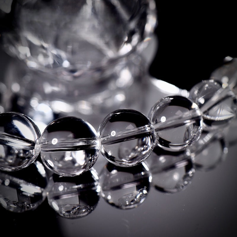 Close-up of clear glass beaded bracelet on reflective black surface
