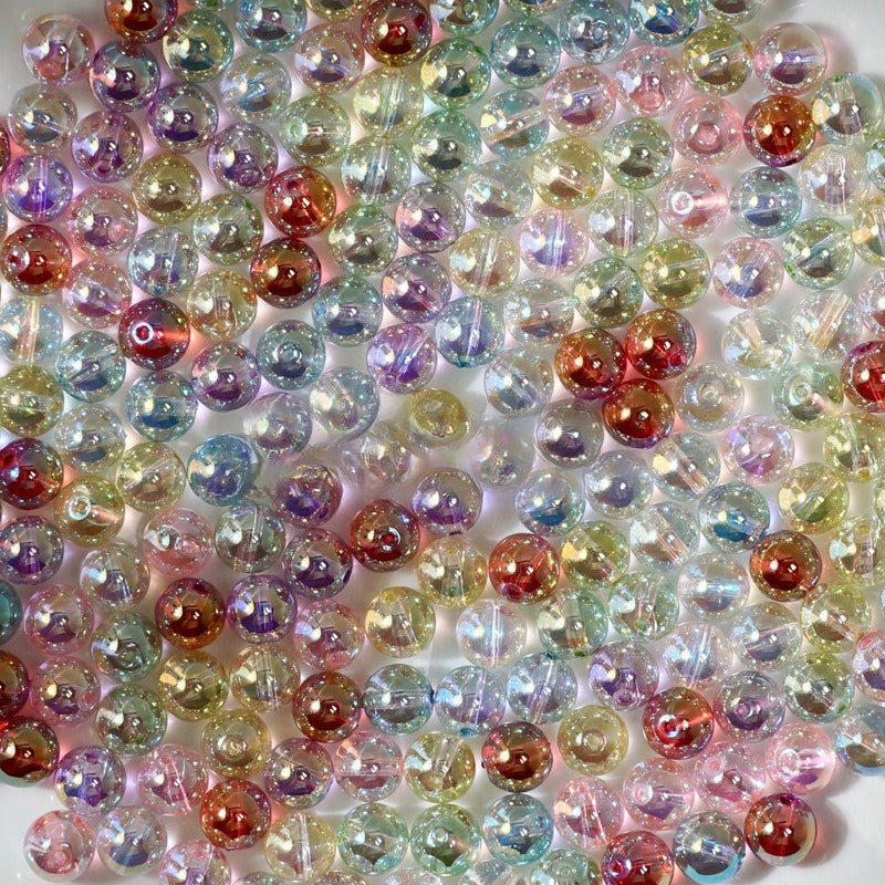 A dense pile of round, iridescent acrylic beads with a double-hole design, showing a rainbow of colors including pink, purple, blue, green, and gold under light.