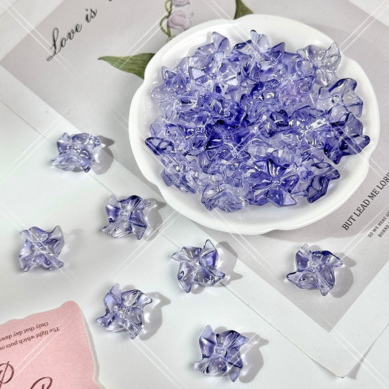 Clear and periwinkle blue translucent 20mm carved glass windmill beads on a white surface with a white dish
