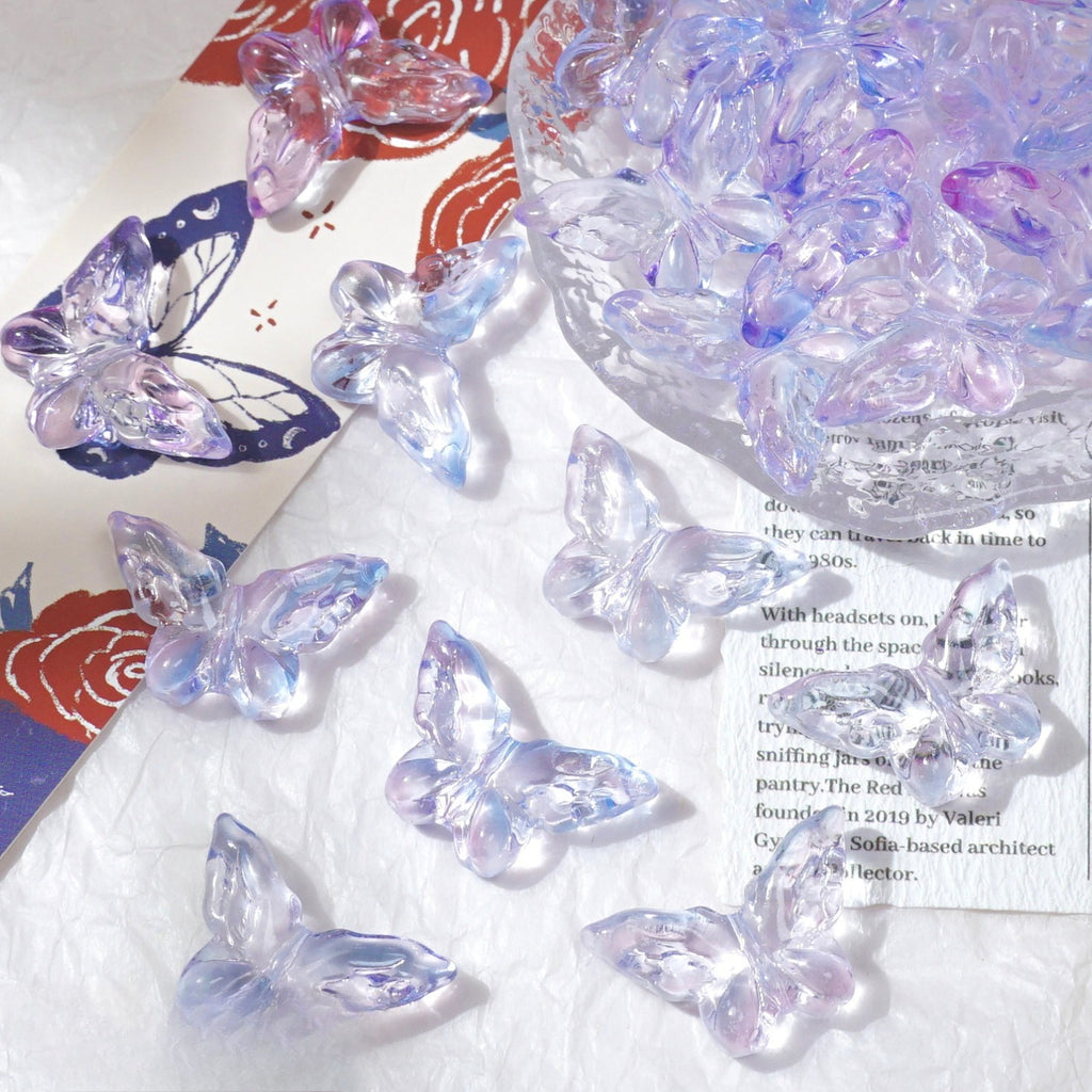 Clear butterfly-shaped glass beads with light purple iridescent sheen scattered on white