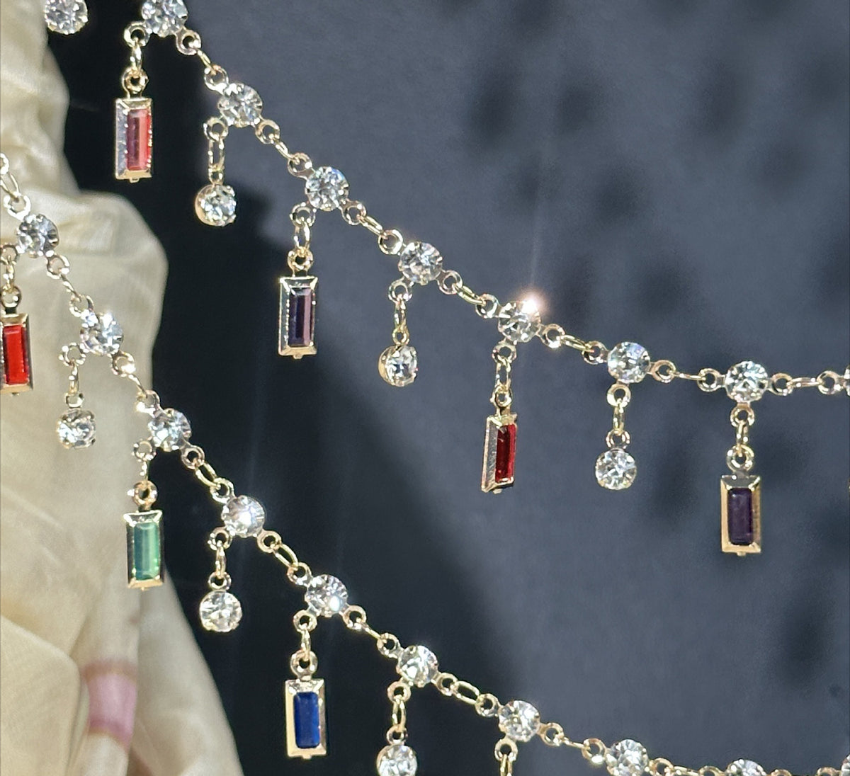 Gold chain with clear round crystal beads and rectangular colored gemstone charms in red, blue, and green