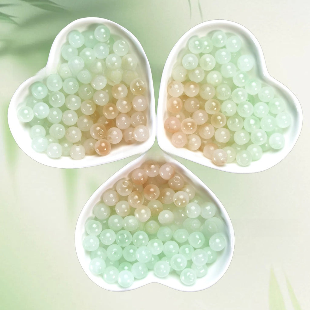 Three heart-shaped bowls of translucent mint, peach, and cream beads