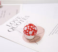 Red mushroom-shaped glass bead with white spots on a 'LOVE QUOTES' card