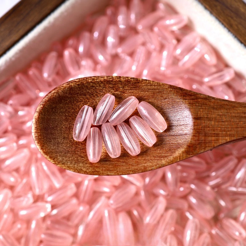 Pink 4x9mm glazed glass long rice beads in a wooden spoon